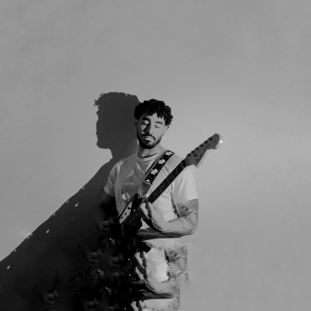 dae zhen playing guitar in the dark, lit by a moving warm light